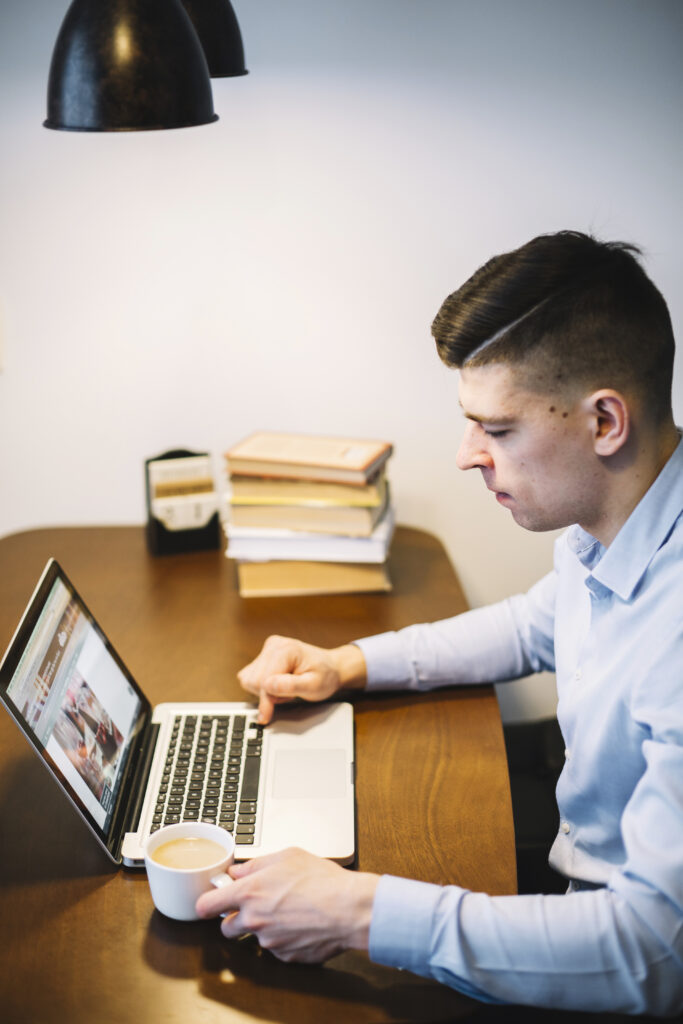 side view man with coffee using laptop